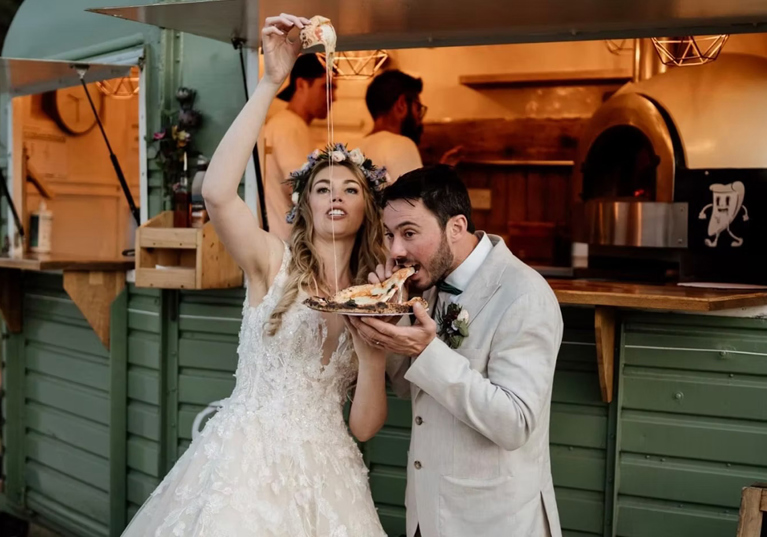 Bride and groom eating pizza in front of Dough Man's Land horsebox